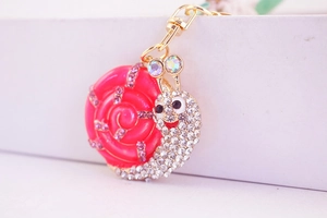 Détail du porte-clés escargot en émail rose avec strass et fermoir en métal doré en D