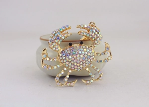 Vue macro d'un pendentif crabe en strass colorés avec finition dorée sur céramique