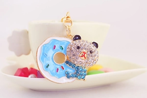 Close-up of rhinestone teddy bear keychain with blue enamel donut and gold plating