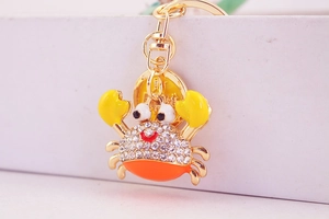 Detail of cartoon crab keychain featuring sparkling rhinestones and golden lucky tag