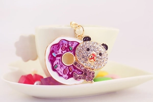Detail of a purple donut and rhinestone bear keychain hanging on a ceramic cup