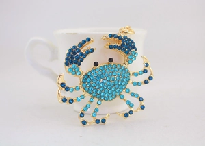 Détail d'un porte-clés crabe orné de strass bleus et d'une finition en métal doré poli