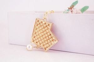Close-up of golden hollow mesh texture and elegant white pearl pendant on a keychain