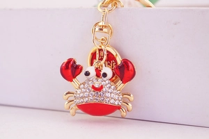 Close-up of golden crab keychain with red enamel claws and sparkling white rhinestones