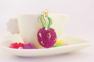 Close-up of a pineapple keychain with pink and green rhinestones on gold metal base