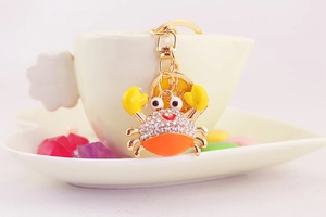 Macro detail of crab keychain with sparkling crystals and golden engraved coin charm