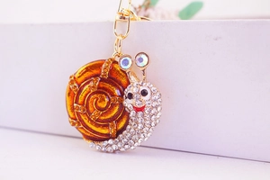 Vue macro du porte-clés escargot en émail orange serti de strass et de cristaux