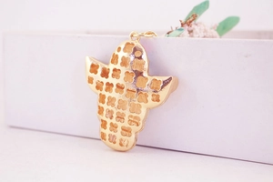 Close-up of golden corn pendant back with hollow clover patterns and fine plating