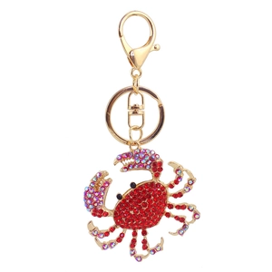 Détail d'un porte-clés crabe en strass rouges avec base dorée et cristaux irisés