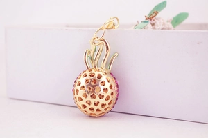 Detailed view of golden pineapple pendant with hollow heart patterns and pink rhinestones