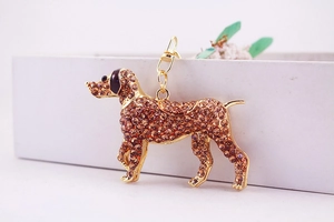 Detailed close-up of golden dog keychain featuring brown rhinestones on a white gift box