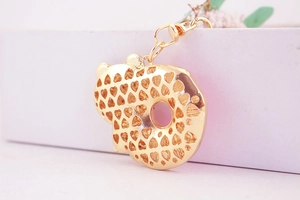 Detail of golden heart-patterned cutout charm on a keychain with lobster clasp