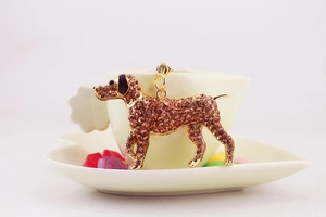 Close-up of a sparkling rhinestone dog keychain pendant hanging on a white ceramic cup