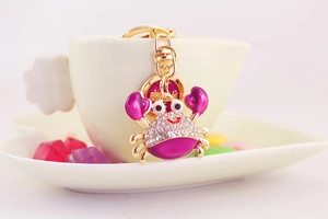 Close-up of purple crab keychain with rhinestones hanging on a white coffee cup