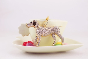 Close-up of a sparkling rhinestone dog keychain hanging on a white coffee cup edge