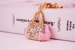 Close-up of pink enamel handbag keychain with white rhinestones and 3D floral details