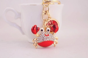Detail of red crab keychain with sparkling rhinestones and a lucky gold coin charm