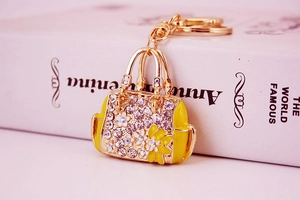 Detailed macro view of a golden handbag keychain with white rhinestones and yellow enamel