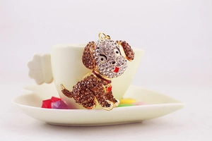 Detail of a sparkling rhinestone dog keychain with a red heart collar on a coffee cup