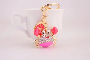 Close-up of pink crystal crab keychain with gold ring and good luck charm pendant