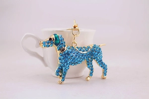 Close-up of golden dog keychain with dark blue rhinestones and green enamel details