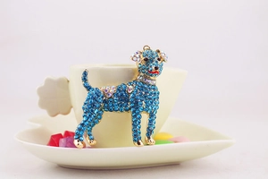 Close-up of golden dog keychain featuring sky blue rhinestones and red enamel detail