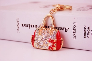 Detailed close-up of a red handbag keychain with sparkling rhinestones and floral accents