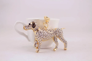 Close-up of golden dog keychain with white rhinestones leaning on a coffee cup