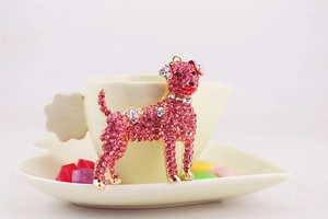 Macro shot of cute puppy keychain with pink rhinestones on a white ceramic cup