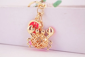 Detailed close-up of a golden filigree crab keychain with red luck charm and metal ring
