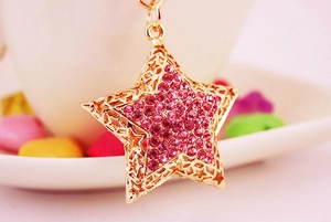 Detailed macro view of a gold pentagram keychain charm with pink rhinestones