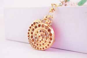 Détail macro du pendentif escargot doré avec texture à pois et chaîne métallique