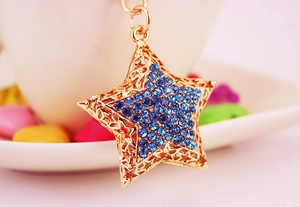 Close-up of golden pentagram keychain with sparkling blue rhinestones and hollow-out star design