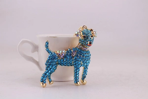 Detailed close-up of blue rhinestone puppy keychain resting on a white ceramic cup