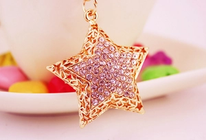 Macro shot of gold pentagram keychain with pink rhinestones and hollow-out star design