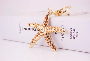 Macro shot of gold starfish keychain with textured metal surface and secure metal ring