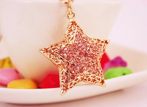Macro shot of gold star keychain with pink rhinestones and hollow-out metal patterns