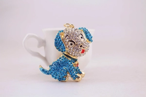Detail of blue rhinestone encrusted puppy keychain on a white ceramic cup