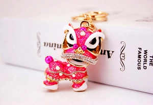 Vue détaillée du porte-clés de danse du lion en émail rose avec strass brillants et perles