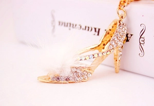 Détail de porte-clés escarpin doré avec pompon en fausse fourrure blanche et cristaux brillants