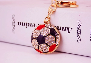 Macro shot of gold football keychain with red black enamel finish and sparkling crystals