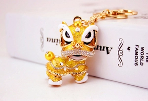 Détail d'un porte-clés lion de danse doré avec émail jaune et strass brillants sur livre