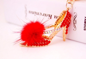 Détail du porte-clés talon haut en strass rouge avec pompon doux sur un livre blanc