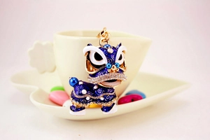 Détail d'un porte-clés danse du lion en émail bleu avec dorure et strass sur une tasse
