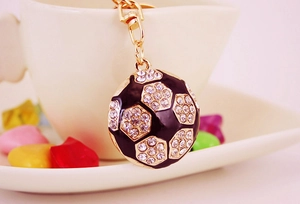 Detail of a sparkling football keychain with rhinestones hanging on a white coffee cup