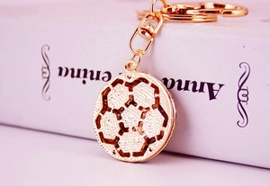 Detailed close-up of a golden metal football keychain with hollow texture and mesh back