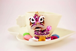 Détail du porte-clés de danse du lion en strass violets sur une tasse décorative