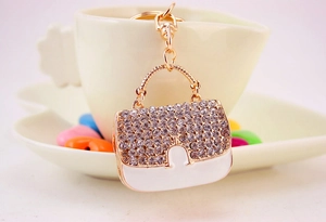 Détail d'un porte-clés mini sac à main avec strass blancs et émail sur alliage doré