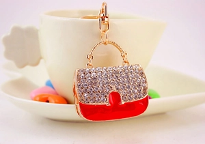 Gros plan du porte-clés sac à main rouge et or orné de strass brillants et mousqueton