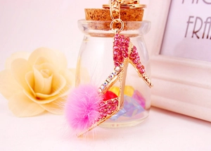 Détail d'un porte-clés escarpin rose serti de cristaux avec un pompon en fourrure douce